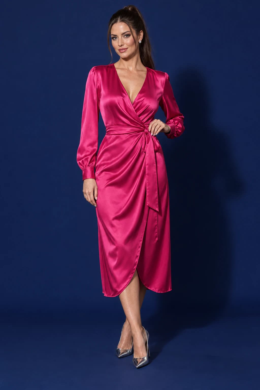 Model in a long-sleeved fuchsia satin wrap dress on a midnight-navy backdrop