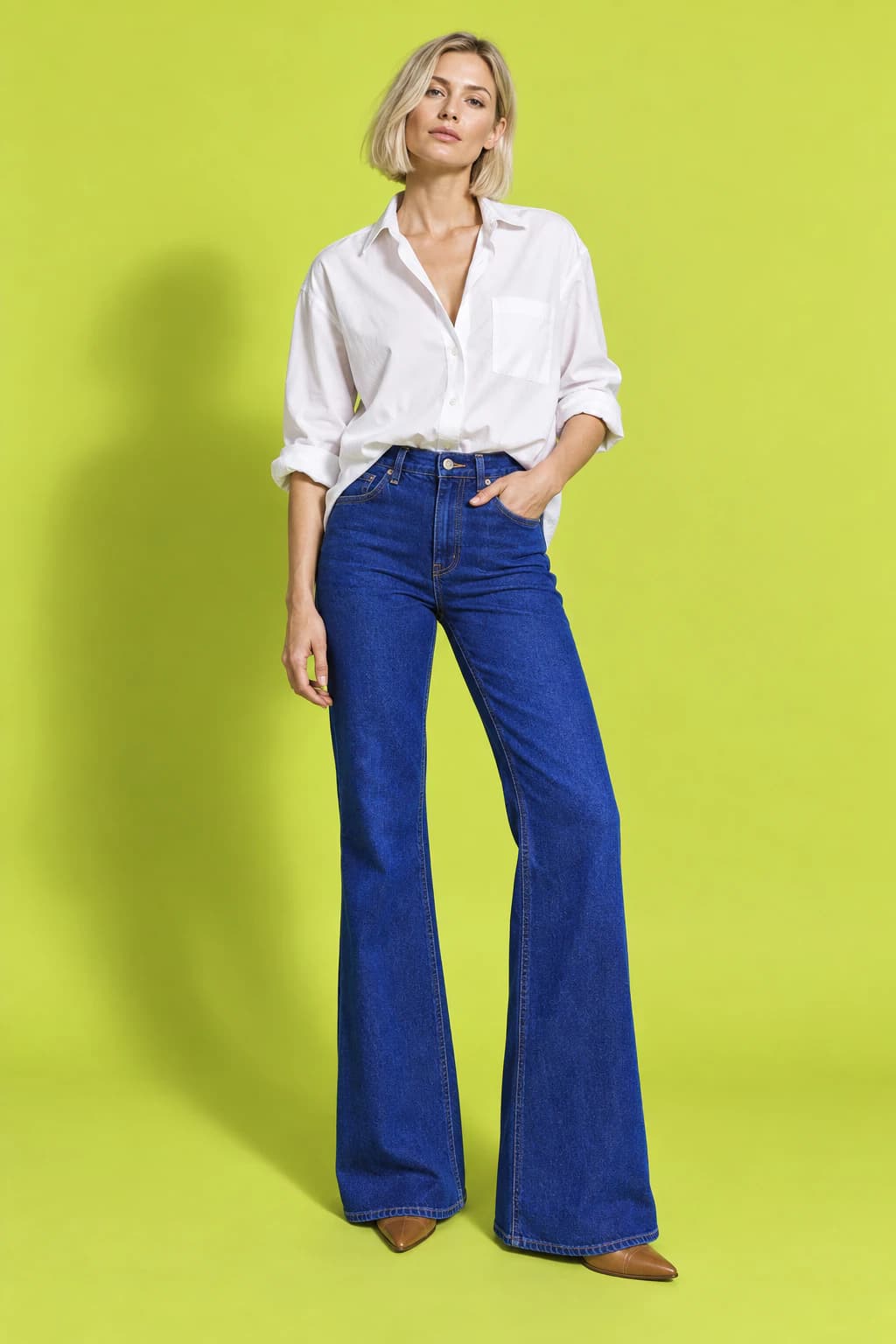Model in high-rise ultramarine flare jeans and a white shirt on a chartreuse backdrop